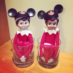 two red and white elf dolls sitting in glasses