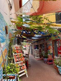 an outdoor market with lots of plants hanging from it's ceiling and colorful decorations on the walls