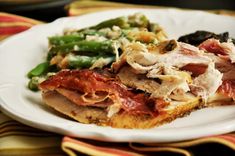 a white plate topped with meat and veggies on top of a striped table cloth