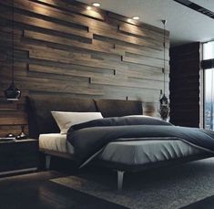 a large bed sitting next to a window in a room with wood paneling on the wall