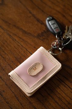 a pink card case with a keychain attached to it on a wooden table