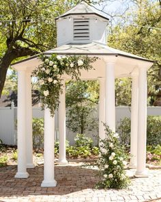 a white gazebo with flowers and greenery around it