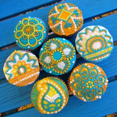 several decorated cupcakes sitting on top of a blue wooden table next to each other