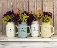 three painted mason jars with flowers in them