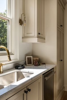 a kitchen sink sitting under a window next to a dishwasher