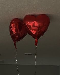 two red heart shaped balloons hanging from the ceiling