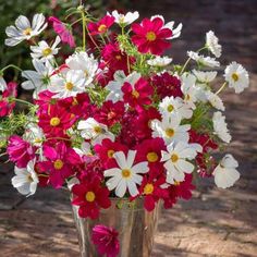 a metal vase filled with lots of red and white flowers