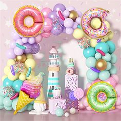 an arch made out of balloons and doughnuts is displayed in front of a pink backdrop