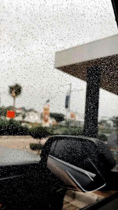 rain is falling down on the windshield of a car as it drives past a gas station