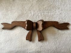 a wooden wall hanging on the side of a white carpeted floor, with two birds carved into it's wings