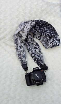 a camera is laying on the snow next to a scarf