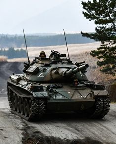 an army tank driving down a dirt road