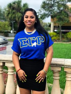 a woman in a blue shirt and black skirt posing for the camera with her hands on her hips