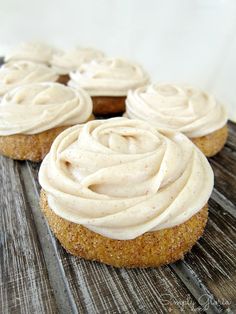 some cupcakes with frosting on top of them sitting on a wooden table