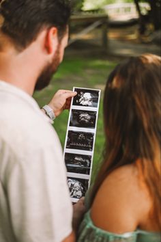 a man and woman standing next to each other looking at pictures on a piece of paper