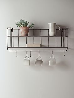 coffee cups and mugs are hanging on a shelf