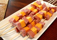 several skewers of meat and cheese on a white plate