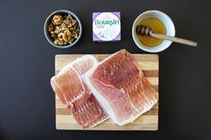 two raw fish fillets on a cutting board next to nuts and honey