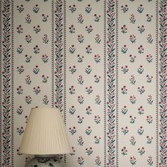 a lamp sitting on top of a table next to a wallpaper covered in flowers