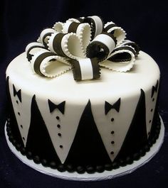 a black and white cake decorated with bow ties on it's top, sitting on a table