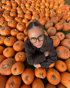 a woman standing in front of a large pile of pumpkins