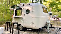 an old camper trailer is parked on the side of the road in front of some picnic tables