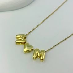 Bring joy and whimsy to your jewelry collection with our Custom Bubble Balloon Letters Necklace. This playful necklace features a delicate gold chain adorned with fun, bubble balloon-shaped letters and special characters like a heart. Perfect for customizing with a name, meaningful word, date, or initials, this necklace adds a touch of lighthearted charm to any outfit. Mother's Day Personalized Letter Beads Initial Necklace, Mother's Day Personalized Initial Necklace With Letter Beads, Mother's Day Personalized Gift Initial Necklace With Letter Beads, Personalized Gold Charm Necklaces With Letter Beads, Gold Initial Pendant Name Necklace For Mother's Day, Gold Charm Necklace Custom Name For Mom, Gold Charm Necklaces With Letter Beads For Mother's Day, Gold Name Necklace With Charms For Mom, Gold Charm Necklace With Custom Name For Mom