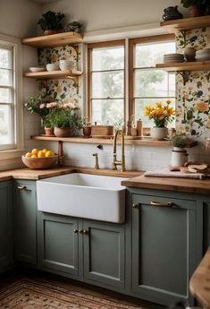 a kitchen with green cabinets and yellow flowers on the window sill above the sink