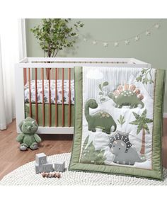 a baby crib bedding set with dinosaurs on it and a teddy bear next to it