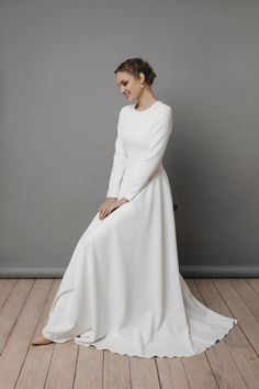 a woman in a white dress sitting on a wooden floor