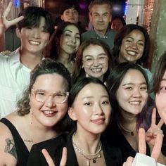 a group of people posing for the camera with their fingers in the shape of two peace signs