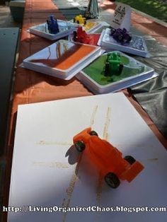 an orange toy car sitting on top of a table next to some paper and markers