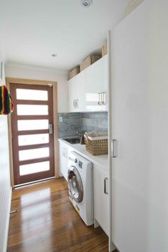 a washer and dryer in a small room next to a door with a basket on it