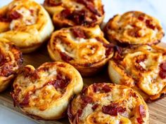 mini pizzas with cheese and bacon are arranged on a cutting board