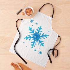 an apron with a blue snowflake design on it next to utensils