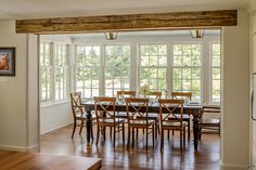 an open kitchen and dining room with wood flooring, white walls and wooden beams