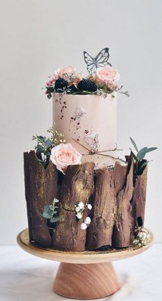 a three tiered cake decorated with flowers and butterflies on top of a wooden stand