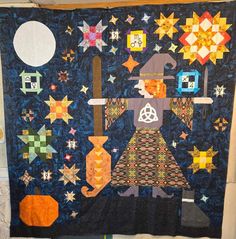 a quilted wall hanging with an image of a wizard holding a broom and stars