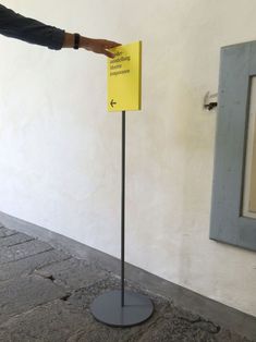 a person reaching for a yellow sign in front of a white wall