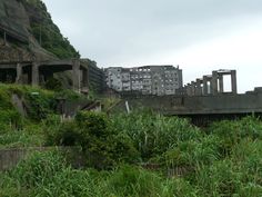 an abandoned building on the side of a hill with trees and bushes in front of it