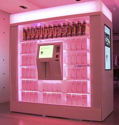 a pink vending machine with lots of bottles on the shelves and lights around it