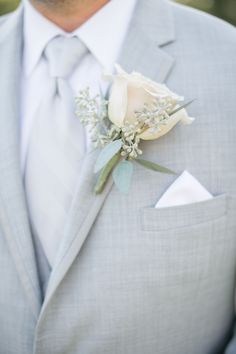 a man in a gray suit with a white rose boutonniere on his lapel