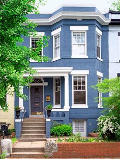 a blue house with steps leading up to the front door and trees on either side