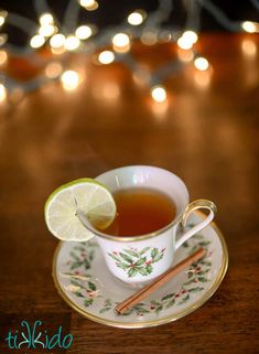 a cup of tea with a slice of lime and cinnamon on the saucer next to it