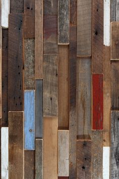 a wooden wall with many different colored boards on it's sides and the bottom half painted red, white, blue, and brown