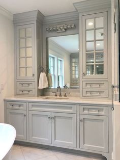 a large bathroom with gray cabinets and white marble counter tops, along with a bathtub