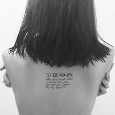 the back of a woman's head with tattoos on her upper and lower back