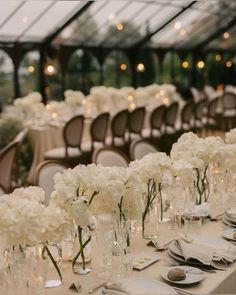 the tables are set with white flowers in vases and place settings for dinner guests