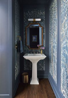 a white pedestal sink sitting under a mirror next to a wall mounted faucet