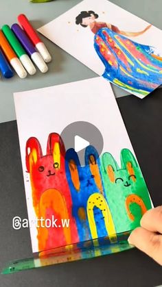 someone is painting pictures on paper with crayons and colored pencils in front of them